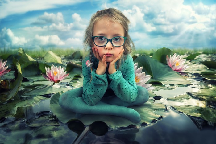 Little girl with glasses among water lilies