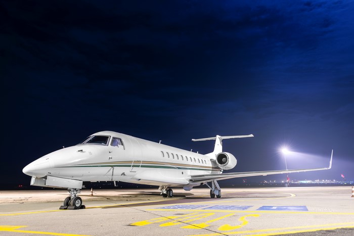 Private jet airplane parked on tarmac at night