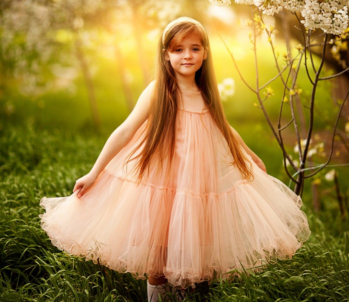 Young girl in a peach dress in a garden