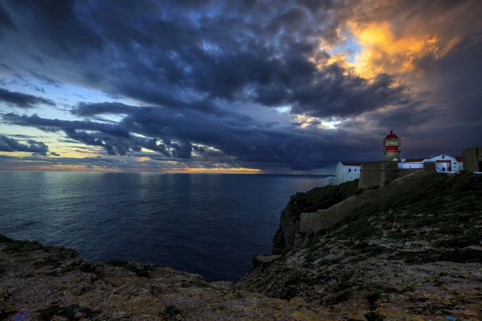 Lighthouse on a cliff overlooking the sea at sunset