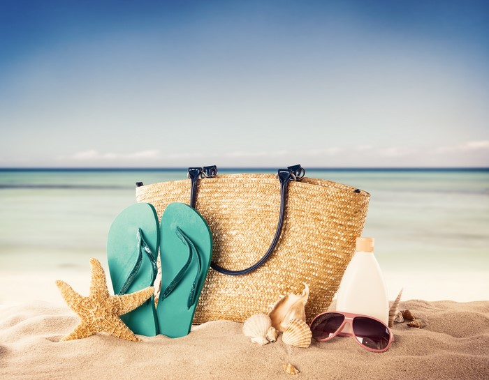 Summer beach accessories on sand with ocean background