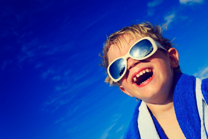 Boy wearing sunglasses against a blue sky