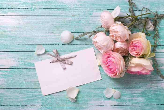 Roses and greeting card on a wooden background