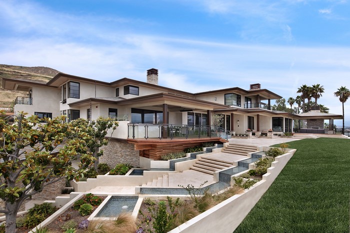 Modern mansion with tiered landscaping and water features