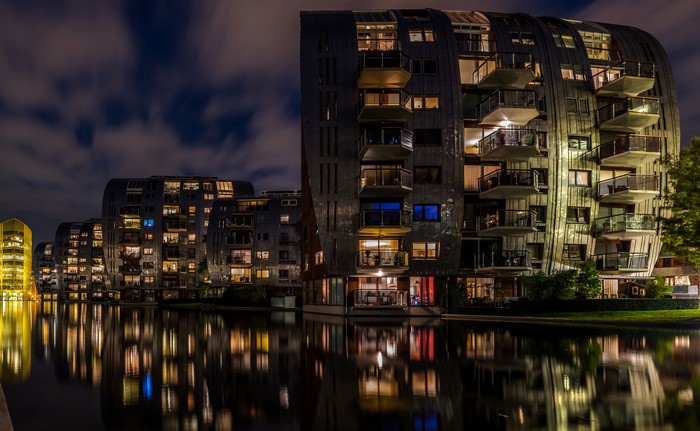Modern apartment buildings at night reflected in a canal
