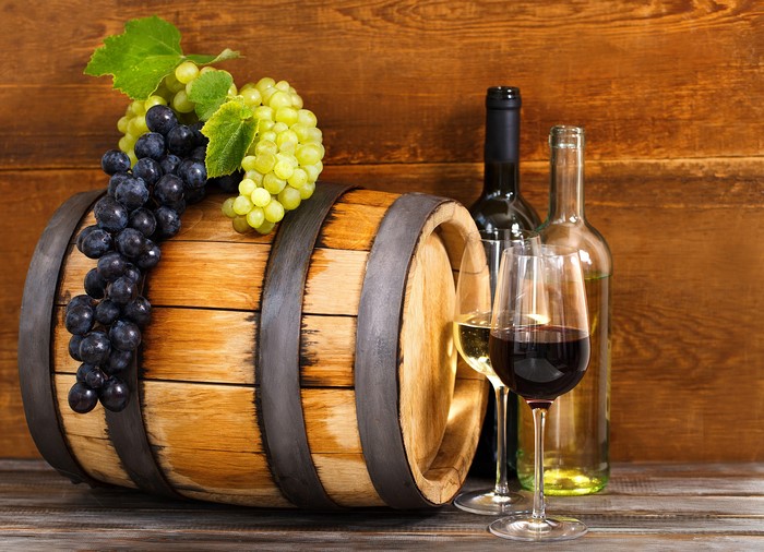 Wine barrel with grapes, bottles, and glasses