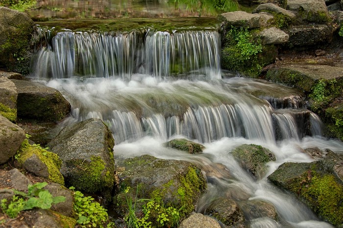 Waterfall over mossy rocks in a park