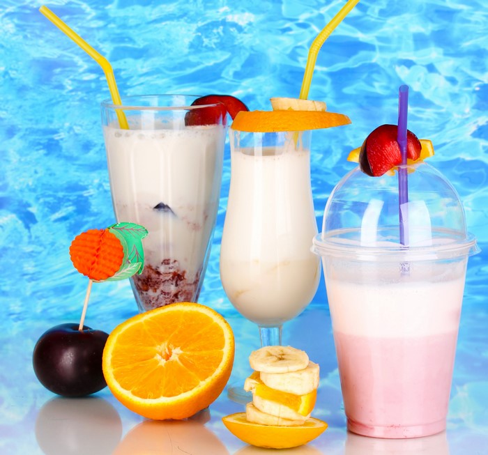Three cocktails with fruits and straws on a blue background