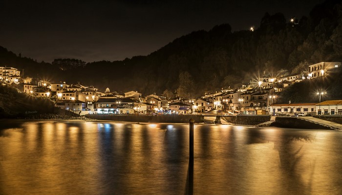 Tazones, Spain at night with illuminated houses and reflections
