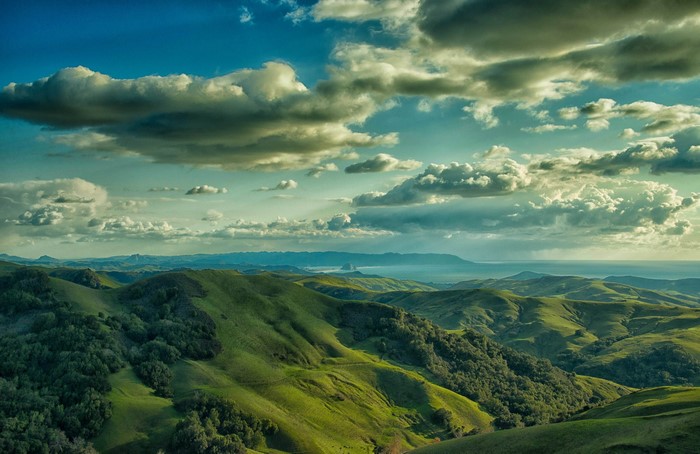 Rolling green hills and clouds over the ocean