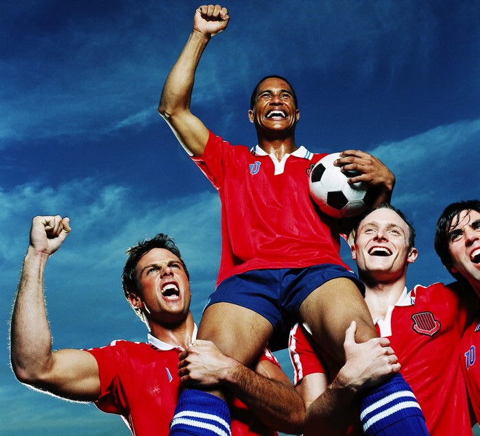 Soccer players celebrating victory with a player on shoulders