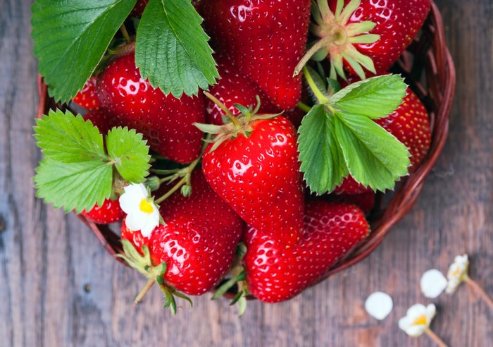 Strawberries in a basket with leaves and flowers