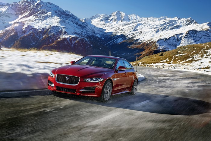 Red Jaguar XE R-Sport driving on a snowy mountain road