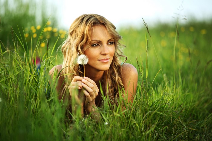 Woman holding a dandelion in a grassy field