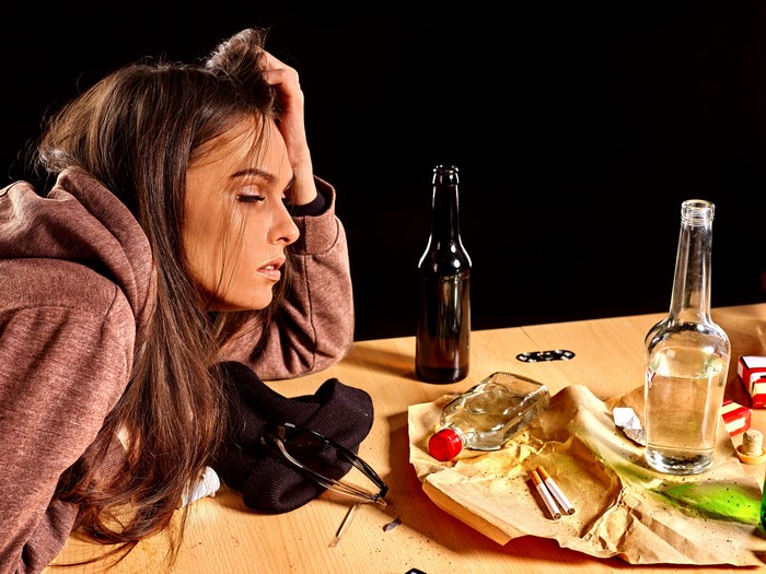 Woman with bottles and cigarettes on table