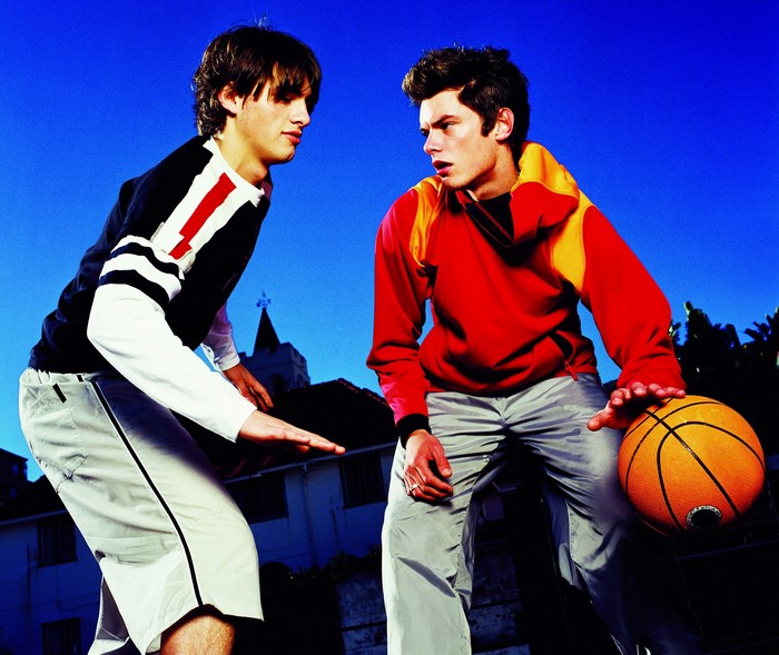 Two young men playing basketball outdoors