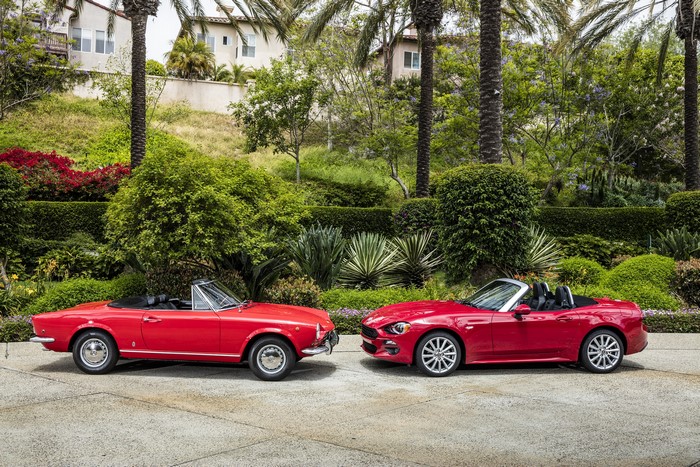 Two red Fiat 124 Spider cabriolets parked outdoors