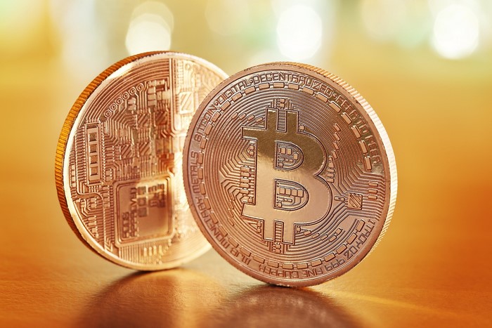 Two Bitcoin coins on a wooden surface