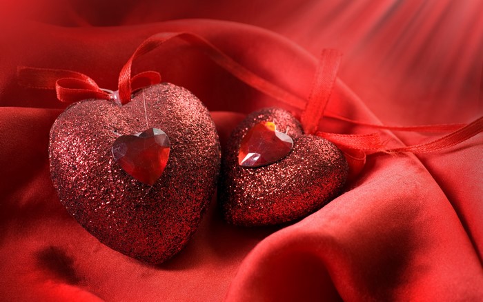 Two red glitter hearts with gems on red silk