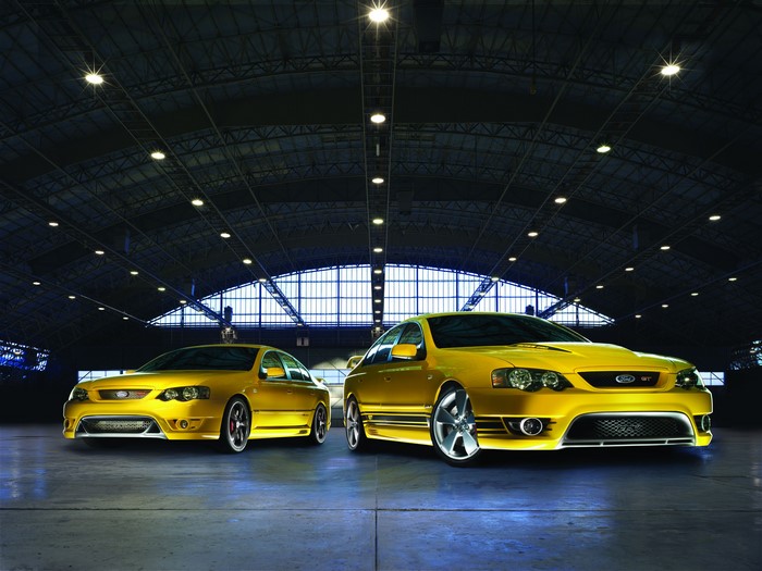 Two yellow Ford FPV GT cars in a warehouse