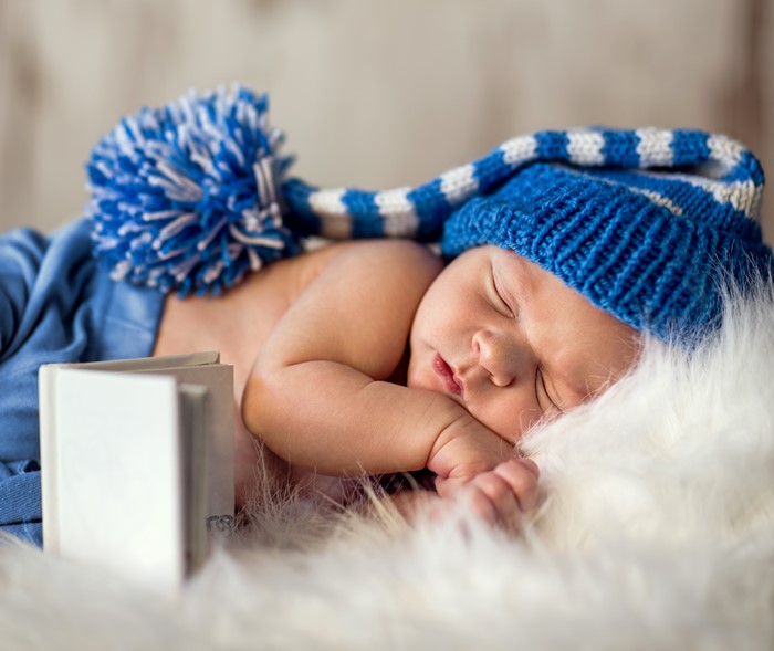 Newborn baby sleeping in a blue winter hat