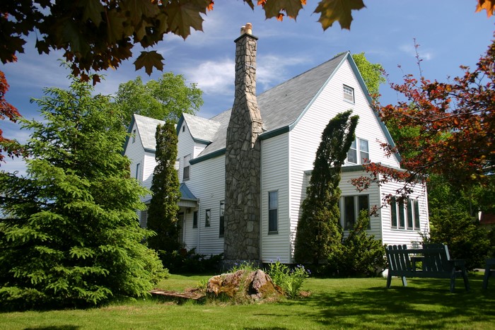 White house with stone chimney and trees