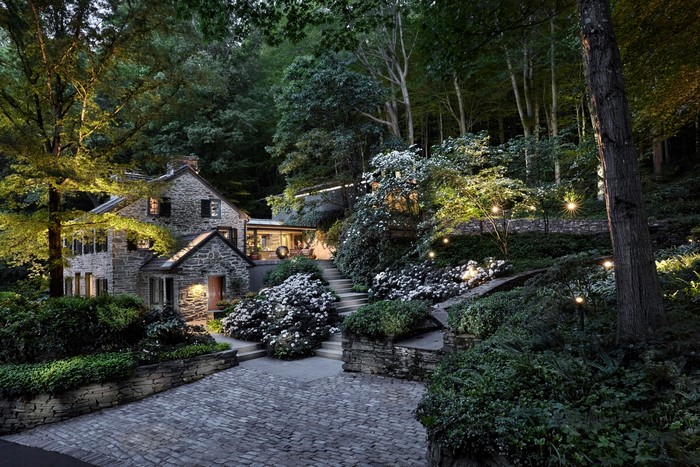 Stone house with illuminated garden at dusk