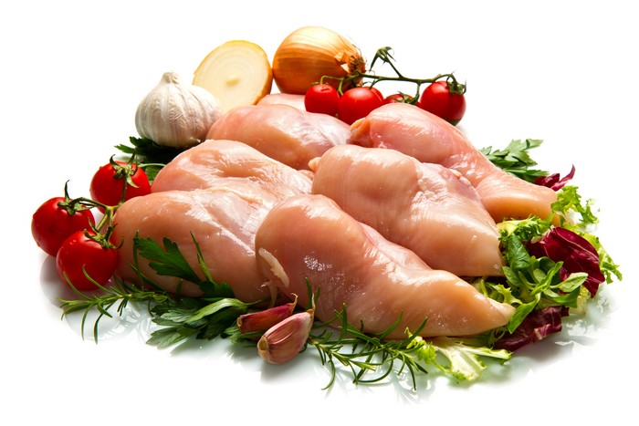 Raw chicken breasts with tomatoes, onions, garlic, and herbs
