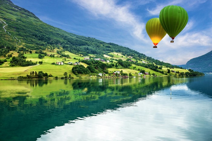Hot air balloons over a Norwegian fjord landscape