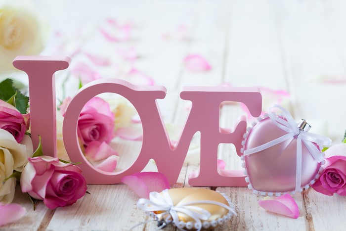 Pink wooden letters spelling LOVE with roses and heart ornaments