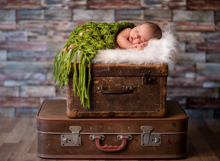 Newborn baby sleeping on suitcases