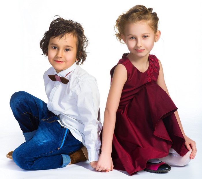 Boy and girl sitting on white background