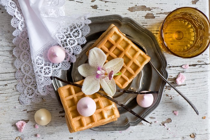 Waffles with orchid, meringues, and glass of amber liquid