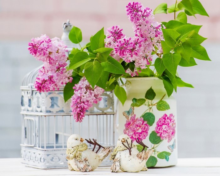 Lilac branches in a vase with decorative birds