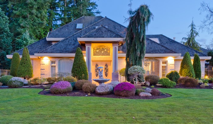 House with manicured shrubs and lawn at dusk