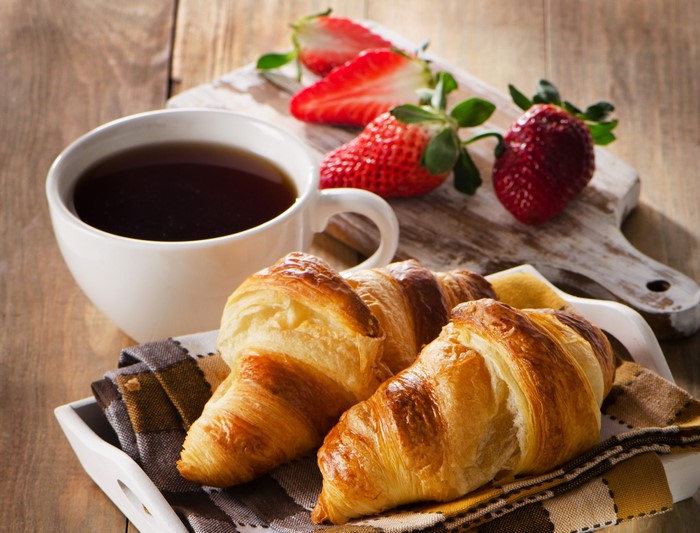 Coffee, Croissants, and Strawberries on a Wooden Table