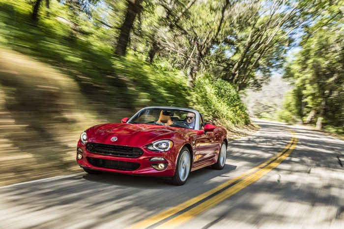 Red Fiat 124 Spider Lusso Cabriolet driving on a road
