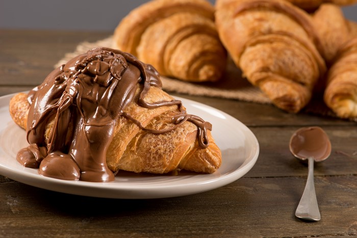 Croissant with chocolate on a plate and spoon