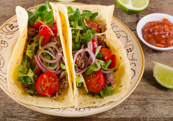Two tacos with ground beef, lettuce, tomatoes, and onions