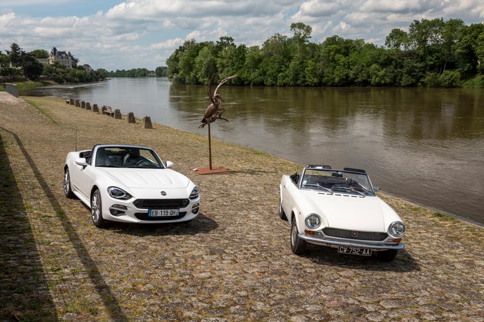 Two white Fiat 124 Spider convertibles by a river
