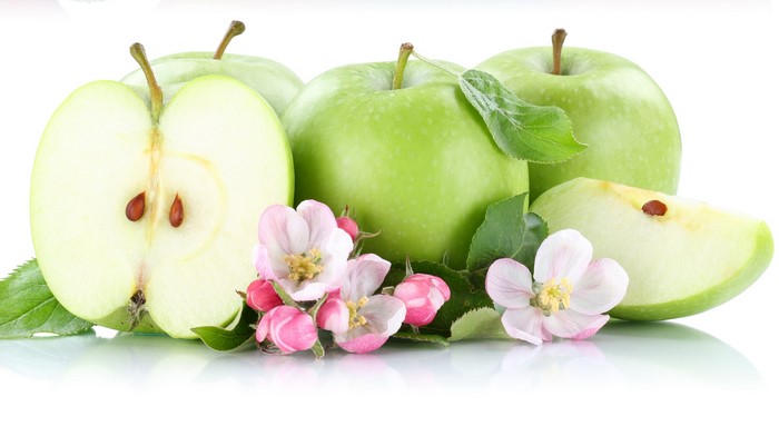 Green apples with blossoms and leaves