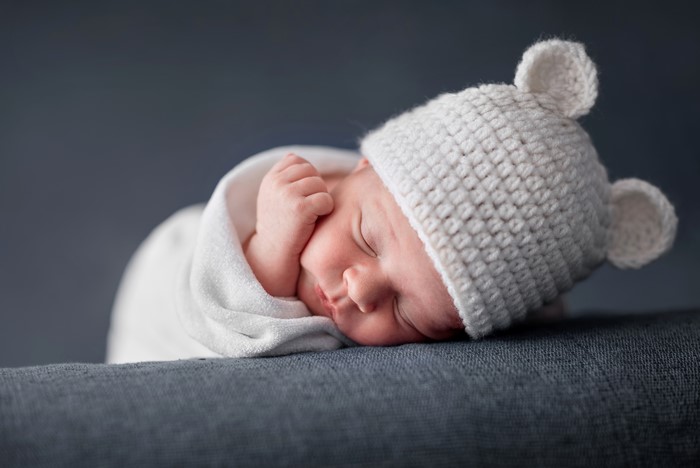 Newborn baby sleeping in a white hat