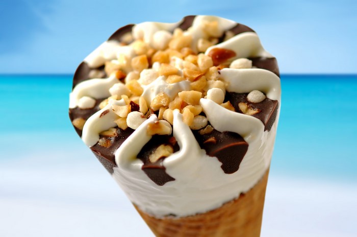 Ice cream cone with chocolate and nuts on beach background