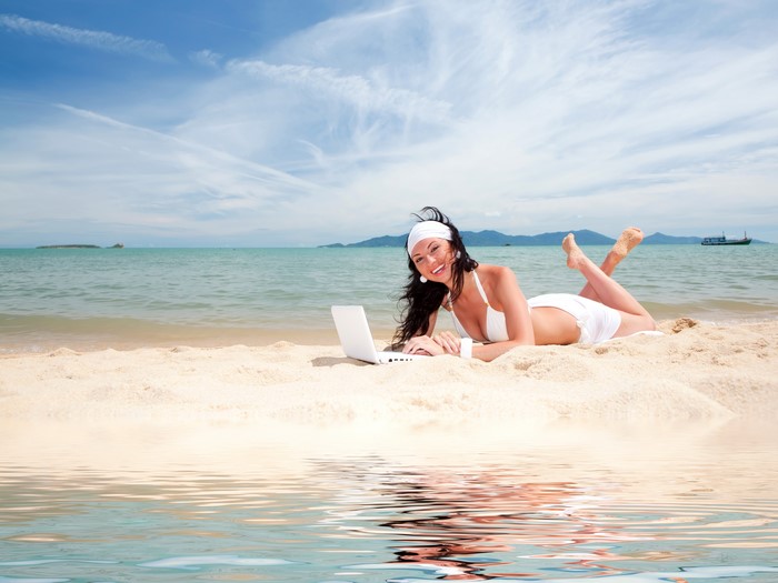 Brunette girl with laptop on beach