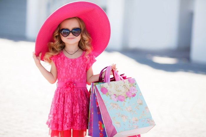 Little girl in pink dress and hat with shopping bags