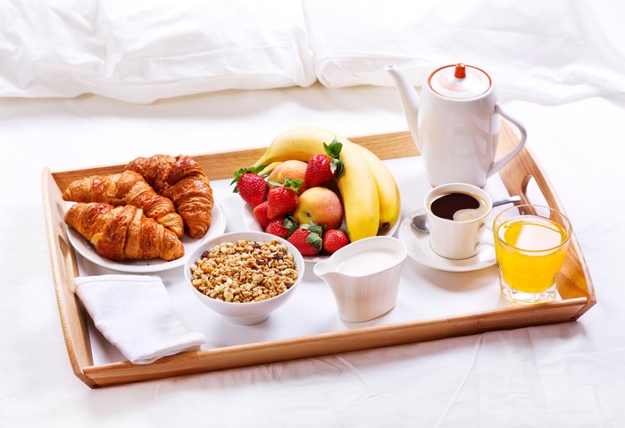 Breakfast tray with croissants, fruit, coffee, and juice