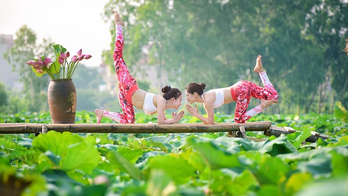 Two Asian women doing yoga in a lotus pond
