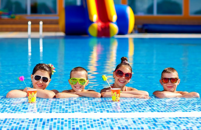 Children in sunglasses by the pool with drinks
