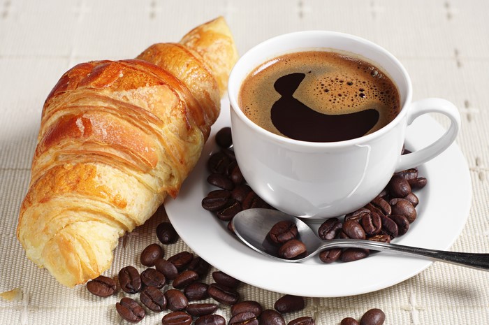 Coffee cup and croissant with coffee beans