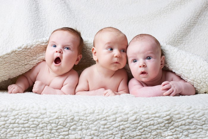Three babies lying on a blanket